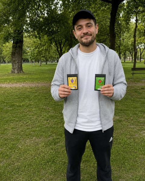 Mann hält ein CBD-Blütentütchen in einem Park mit Bäumen im Hintergrund